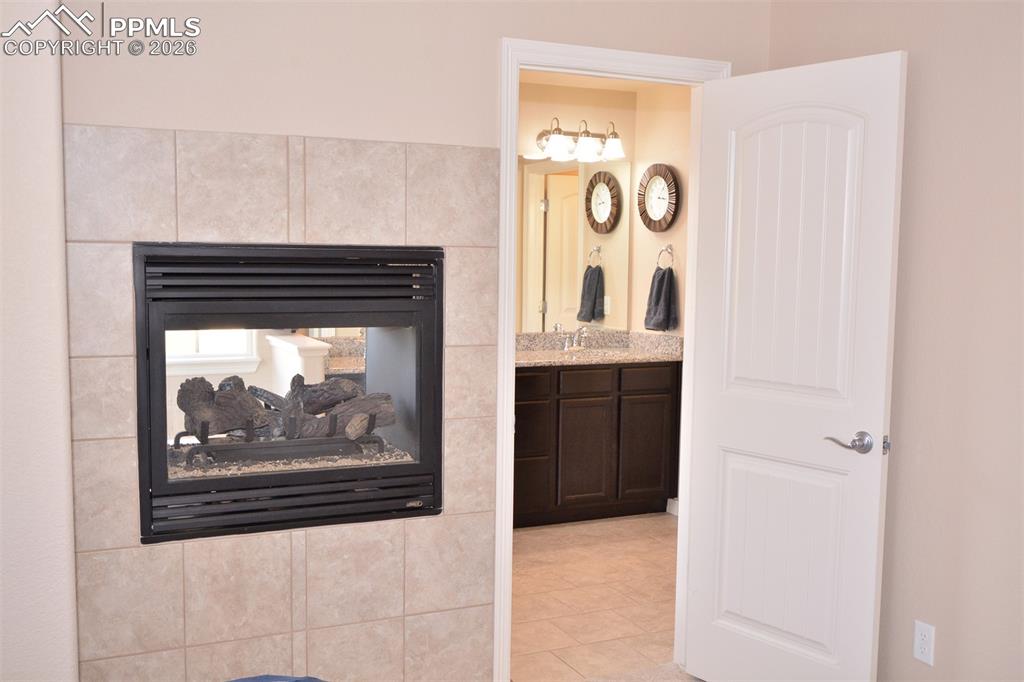 Image 18 of 30: Double sided fireplace in primary bedroom