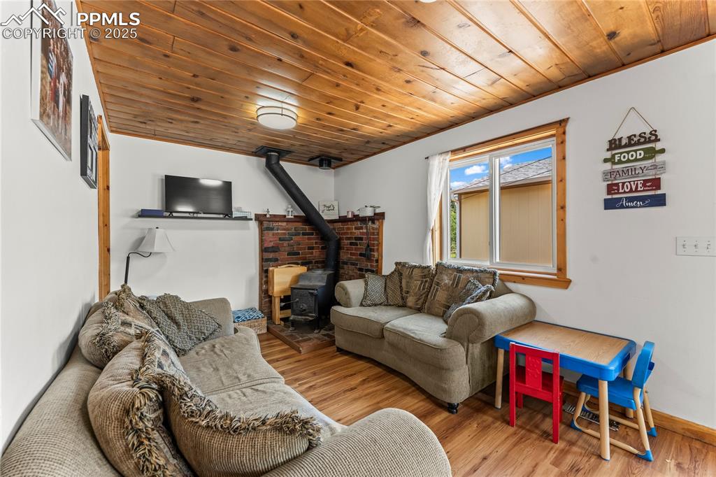 Image 11 of 30: Living area with a wood stove, wood ceiling, and wood finished floors