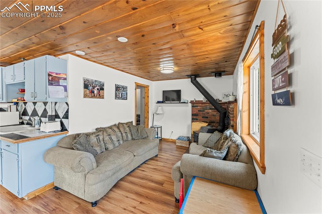 Image 12 of 30: Living room featuring a wood stove, wood ceiling, and light wood-style floo