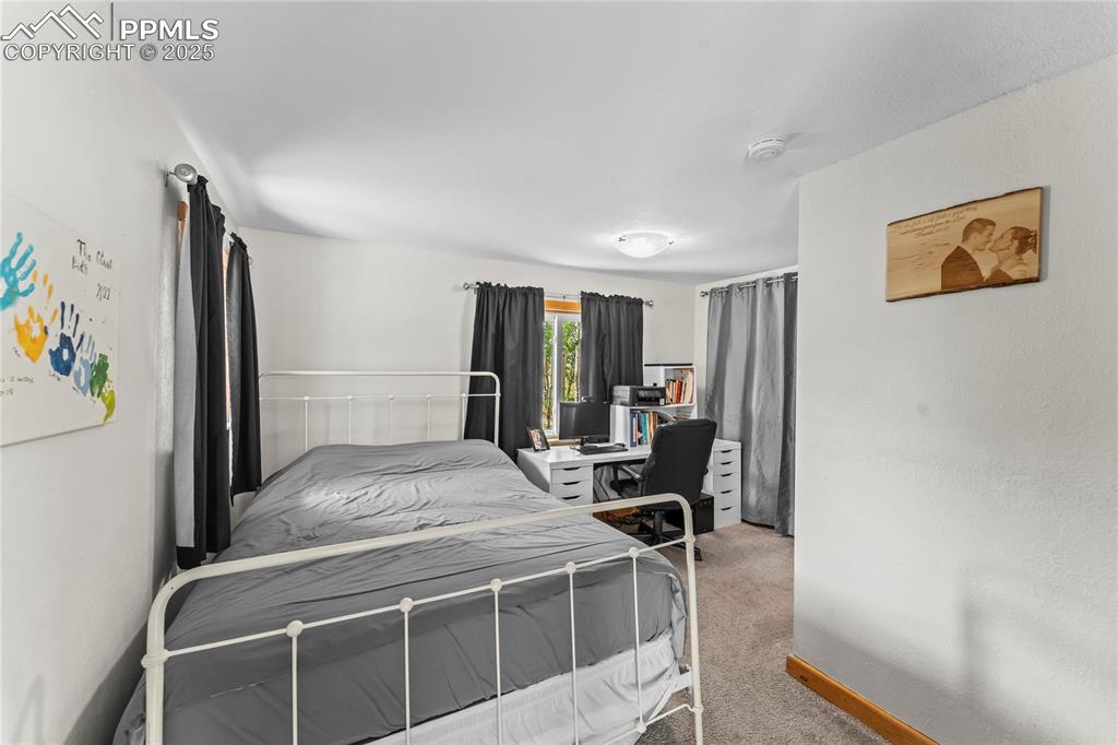 Image 13 of 30: Bedroom featuring light colored carpet and an office area