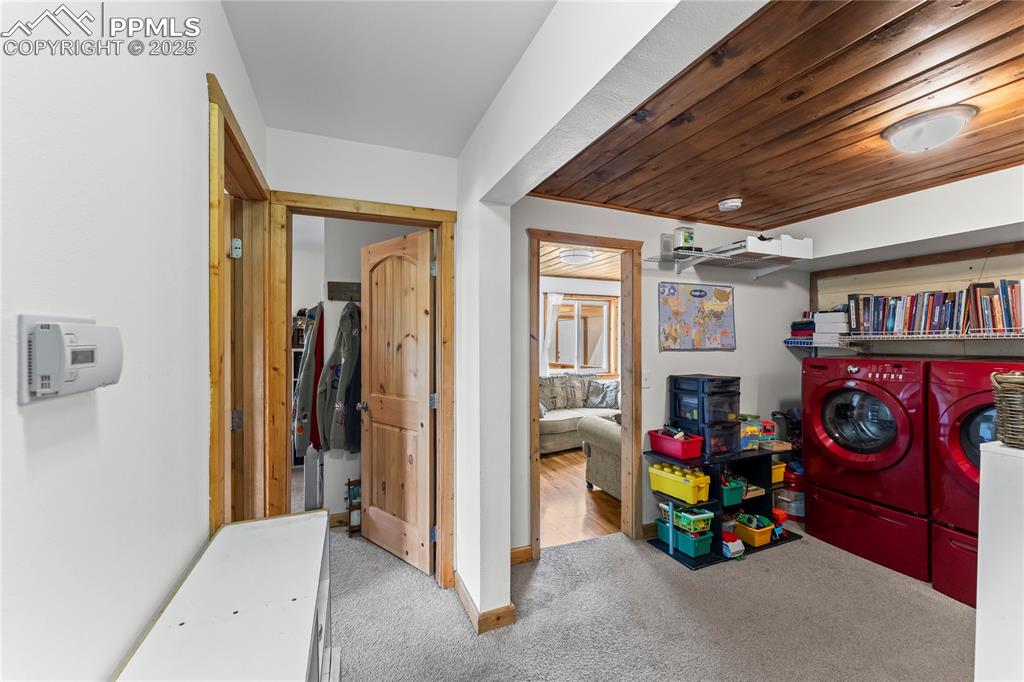 Image 18 of 30: Laundry room featuring washing machine and dryer, carpet flooring, and wood