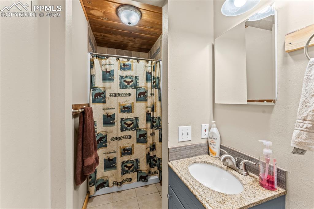 Image 20 of 30: Bathroom featuring vanity, light tile patterned floors, a shower with showe