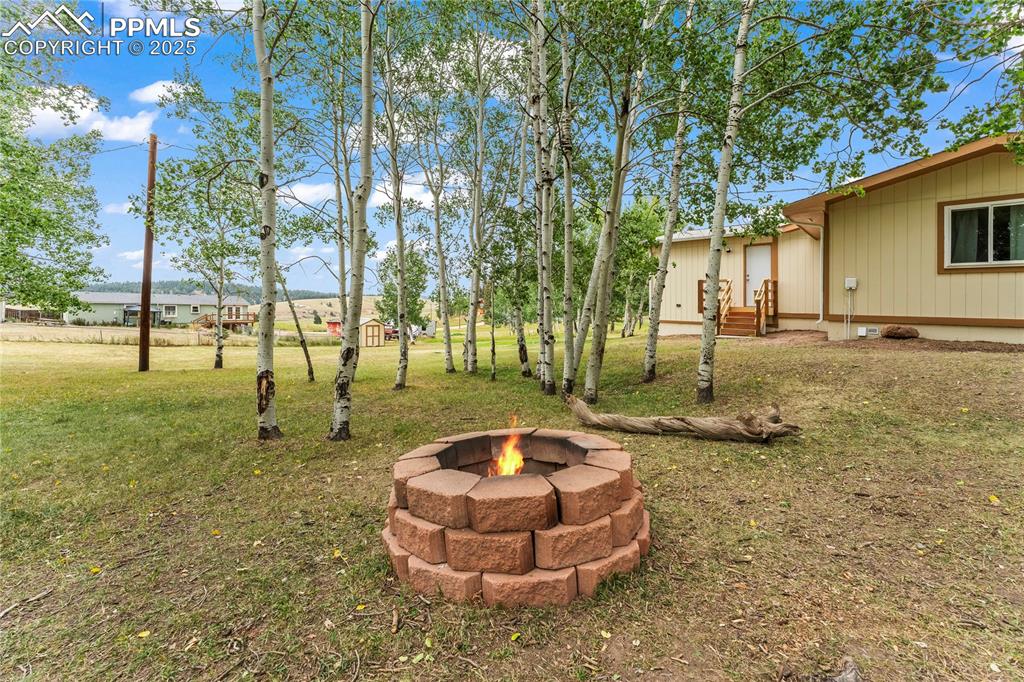 Image 25 of 30: View of grassy yard with a fire pit