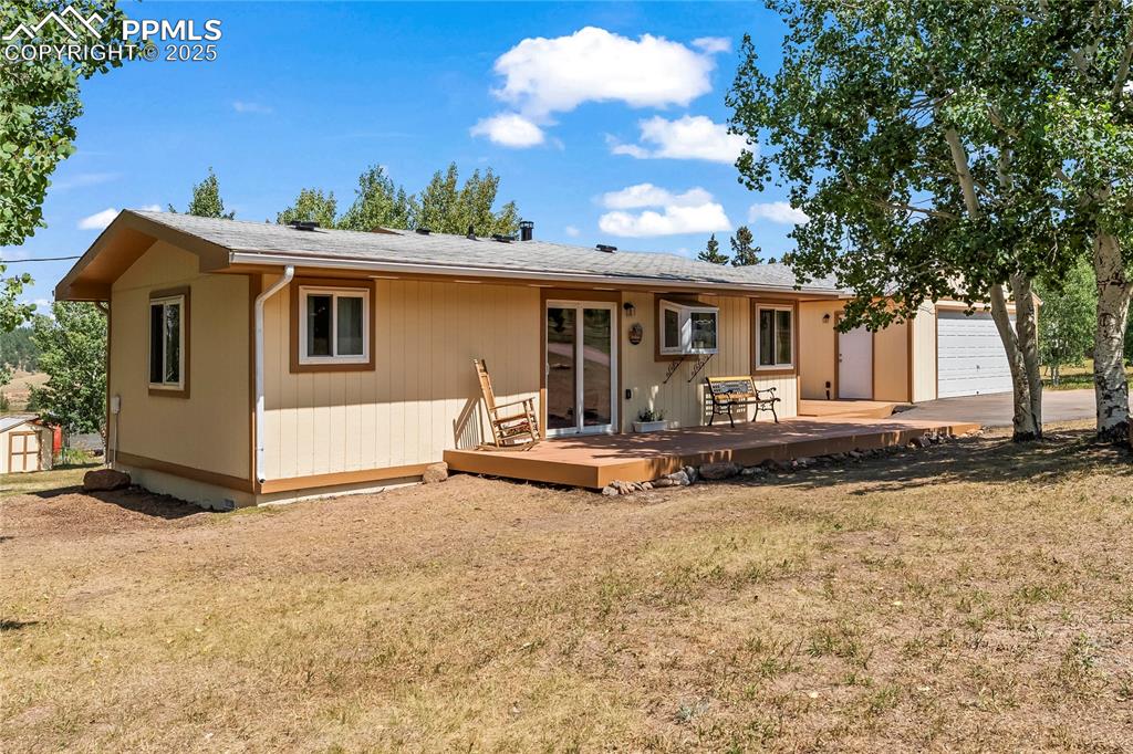 Image 4 of 30: Front view of property featuring a yard, a garage, a deck, and roof with sh