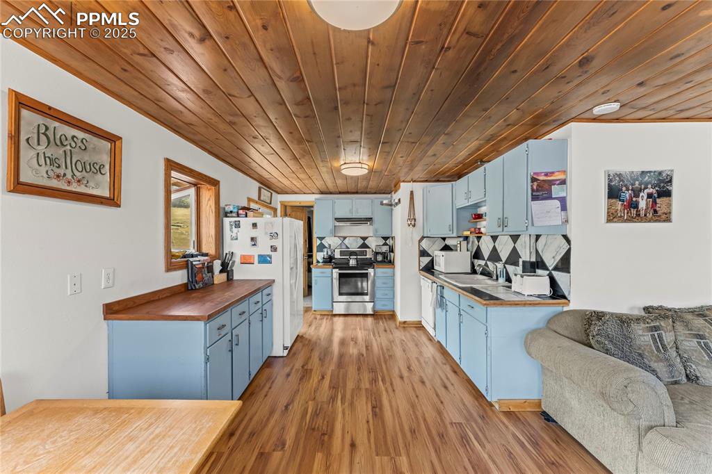 Image 6 of 30: Kitchen with blue cabinets, appliances, light wood-style flooring