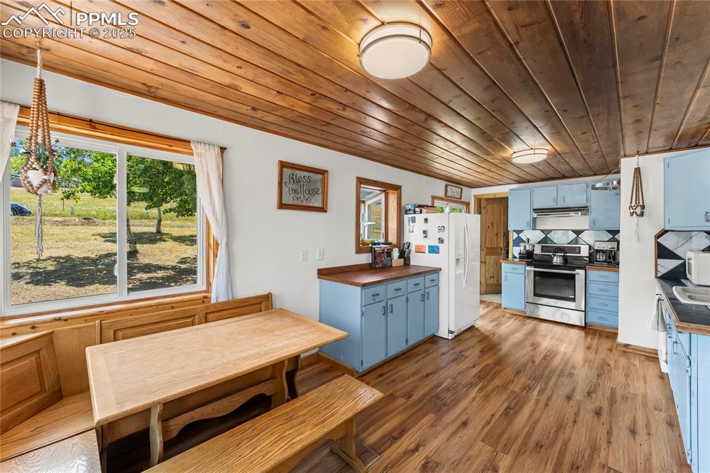 Image 7 of 30: Kitchen with blue cabinets, appliances, light wood-style flooring