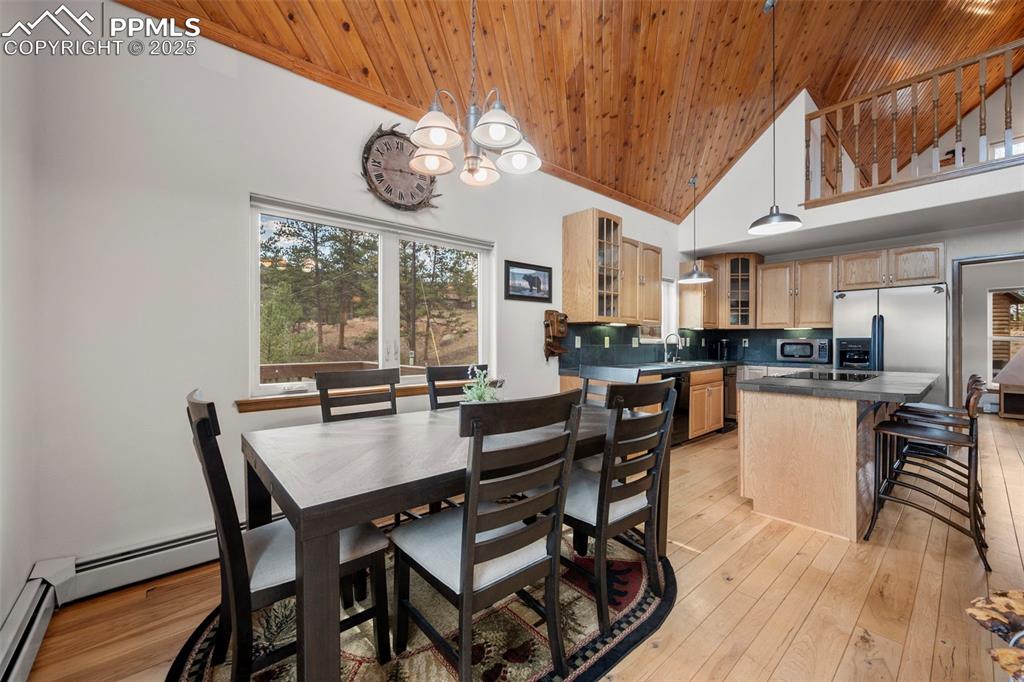 Image 10 of 38: Dining space featuring high vaulted ceiling, light wood-style flooring, woo