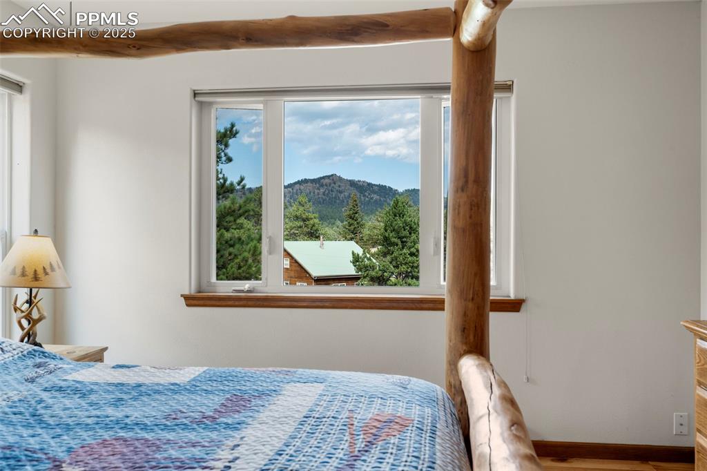 Image 12 of 38: Bedroom featuring a mountain view, wood finished floors, and beamed ceiling