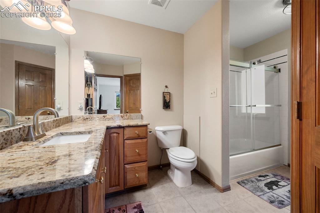 Image 13 of 38: Bathroom featuring vanity, enclosed tub / shower combo, and light tile patt