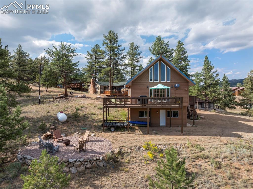 Image 21 of 38: Back of house featuring a wooden deck, an outdoor fire pit, and stairway