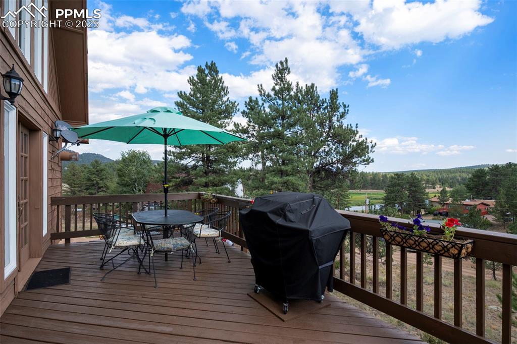Image 24 of 38: Wooden terrace featuring outdoor dining space and area for grilling
