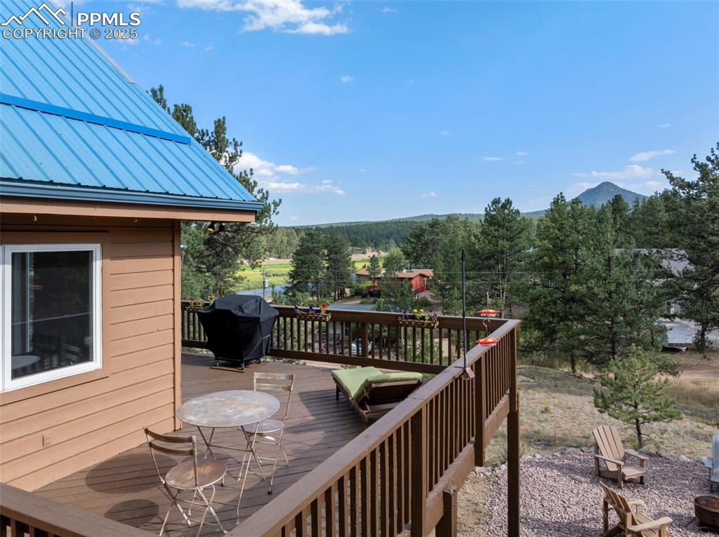 Image 25 of 38: Wooden deck featuring grilling area, a mountain view, and an outdoor fire p