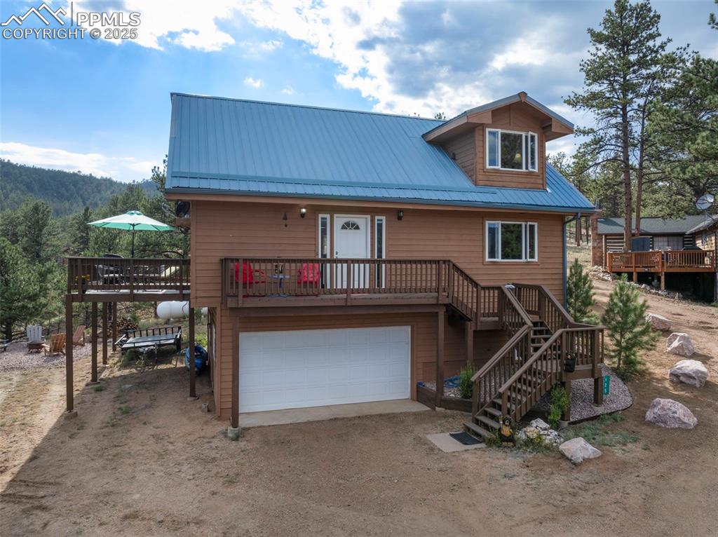 Image 38 of 38: Chalet / cabin with a wooden deck, stairway, a metal roof, and driveway