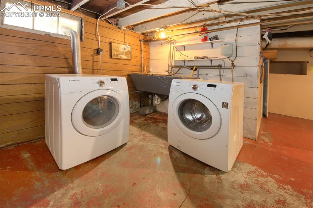 Image 20 of 28: Laundry area with washing machine and clothes dryer and wood walls