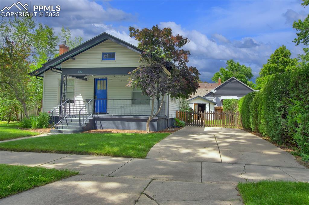 Image 27 of 28: Shotgun-style home with covered porch and a chimney
