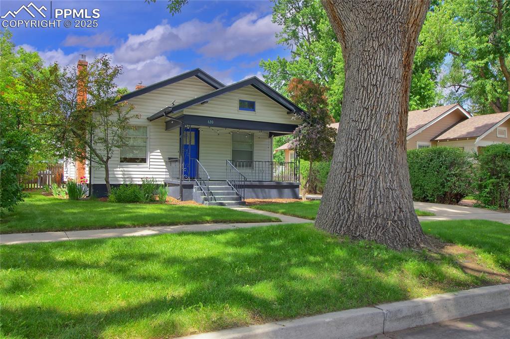 Image 28 of 28: View of front of house with a porch, a front yard, and a chimney