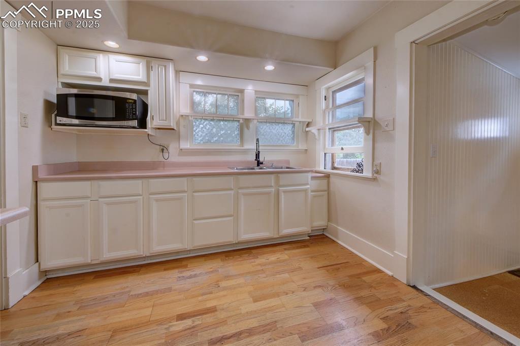 Image 9 of 28: Kitchen featuring stainless steel microwave, light wood-type flooring, whit