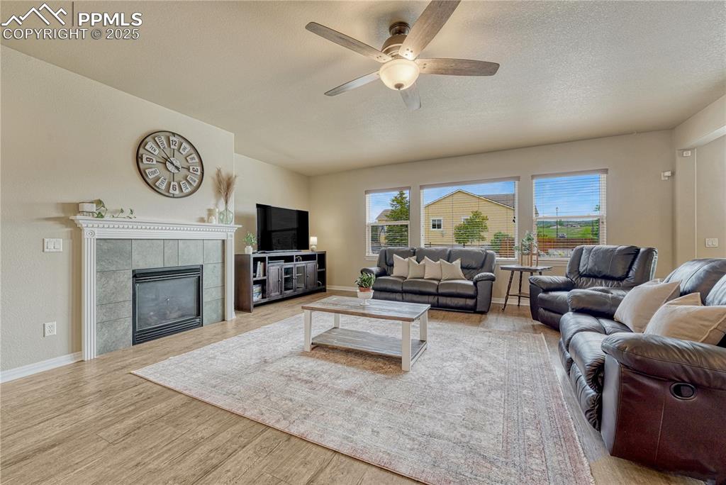 Image 10 of 47: Living area featuring a tile fireplace, light wood-style floors, a ceiling