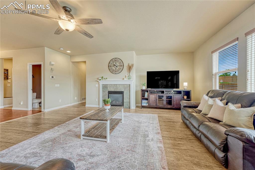 Image 12 of 47: Living room with a tiled fireplace, light wood finished floors, and ceiling