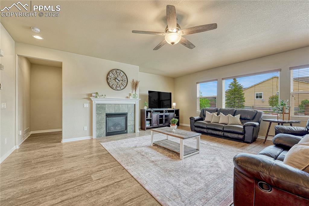 Image 13 of 47: Living area featuring a tiled fireplace, light wood finished floors, a ceil