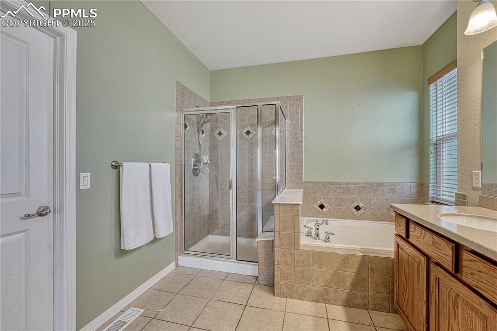 Image 18 of 47: Bathroom with vanity, a bath, a shower stall, and light tile patterned floo