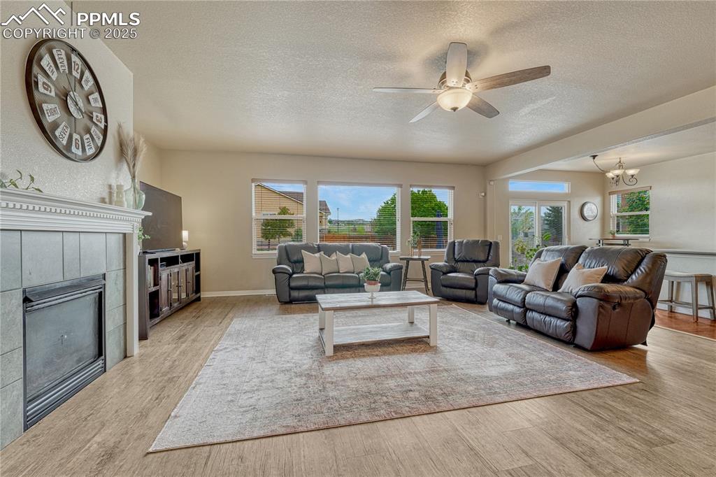 Image 2 of 47: Living area with a tile fireplace, a textured ceiling, healthy amount of na