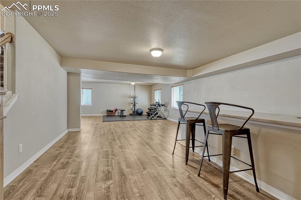 Image 24 of 47: Exercise room featuring a textured ceiling and light wood finished floors