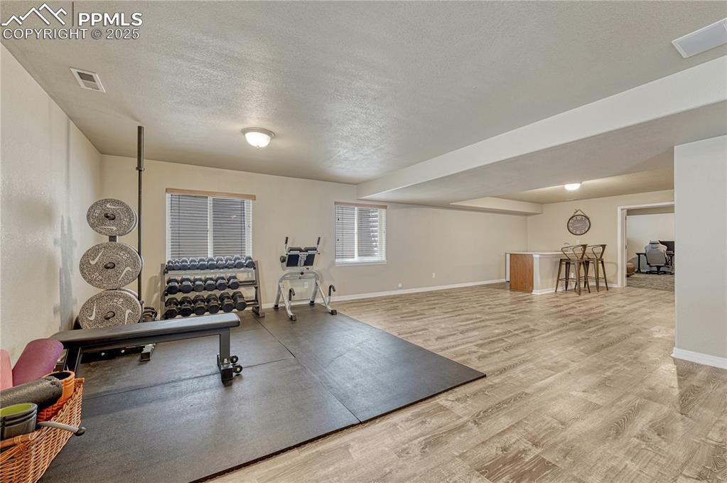 Image 26 of 47: Workout room with a textured ceiling and light wood-style flooring