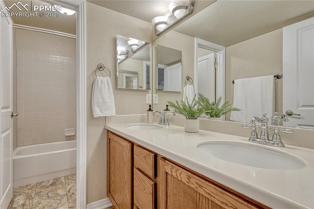 Image 31 of 47: Bathroom with shower / bath combination, double vanity, a textured wall, an