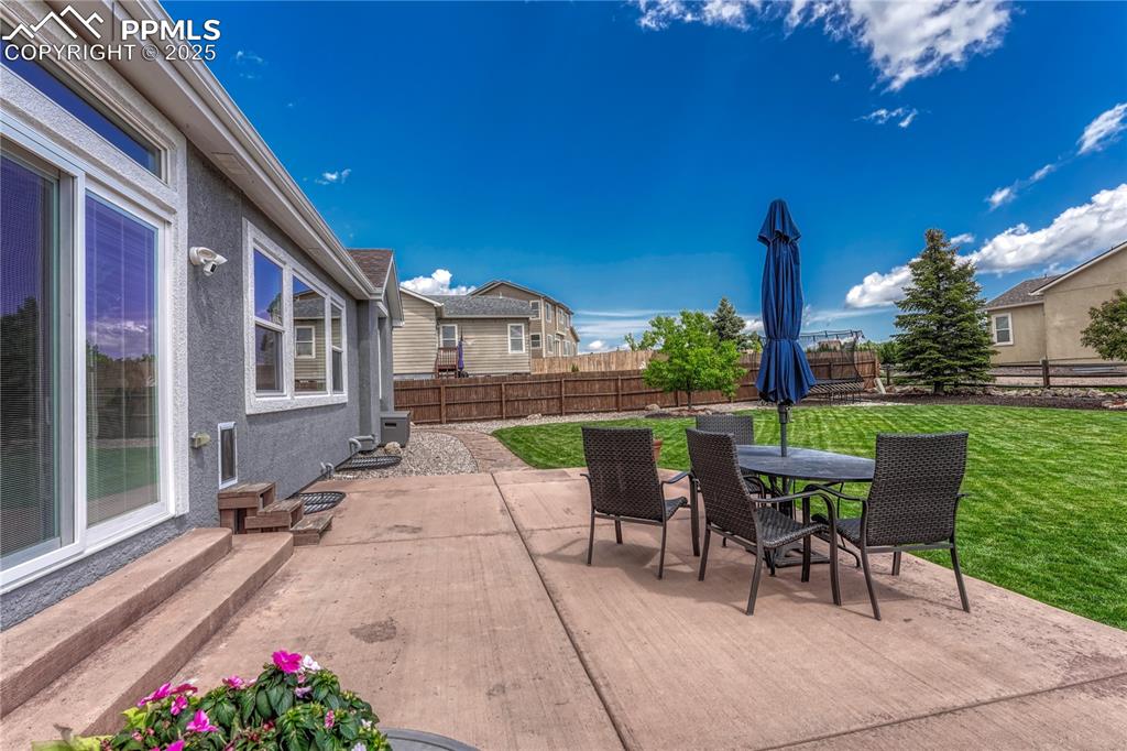 Image 35 of 47: Fenced backyard with a patio area and outdoor dining space