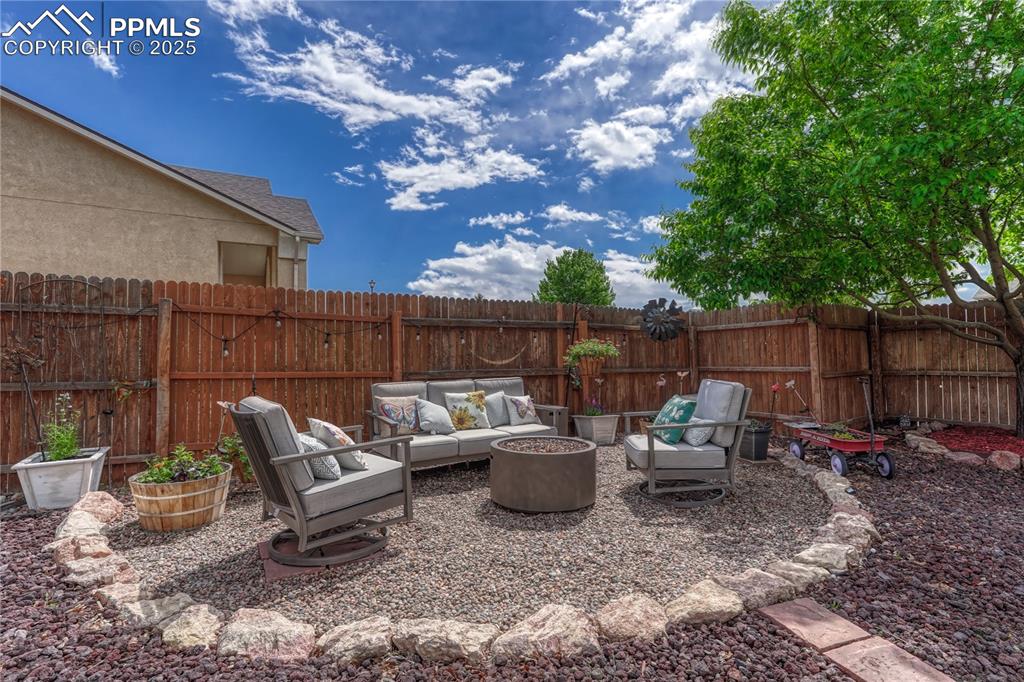 Image 37 of 47: Fenced backyard with an outdoor living space with a fire pit and a patio