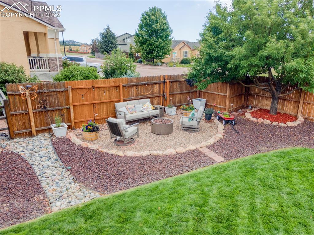 Image 38 of 47: Fenced backyard with an outdoor living space with a fire pit and a patio