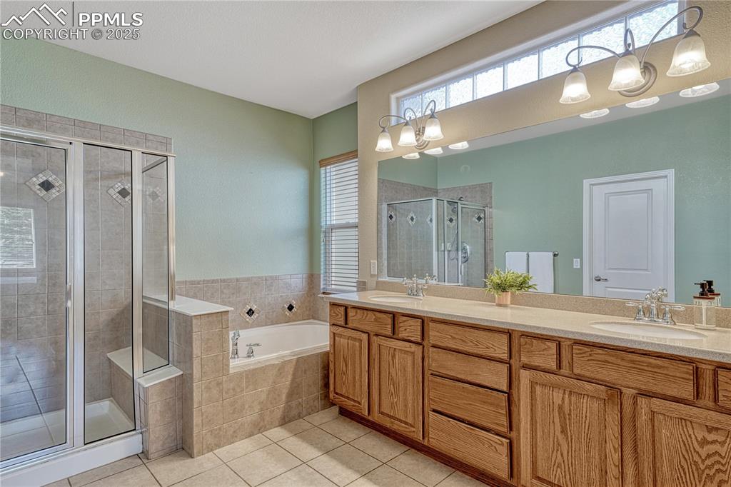 Image 5 of 47: Full bathroom featuring a garden tub, a shower stall, double vanity, and li