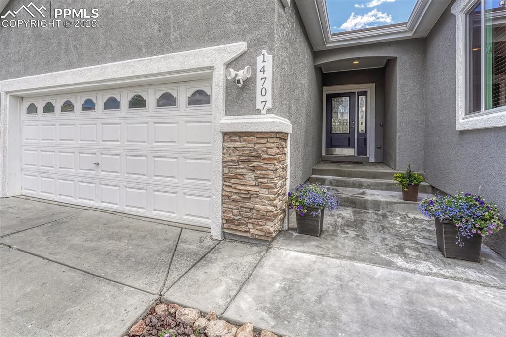 Image 8 of 47: View of exterior entry featuring stone siding, stucco siding, driveway, and