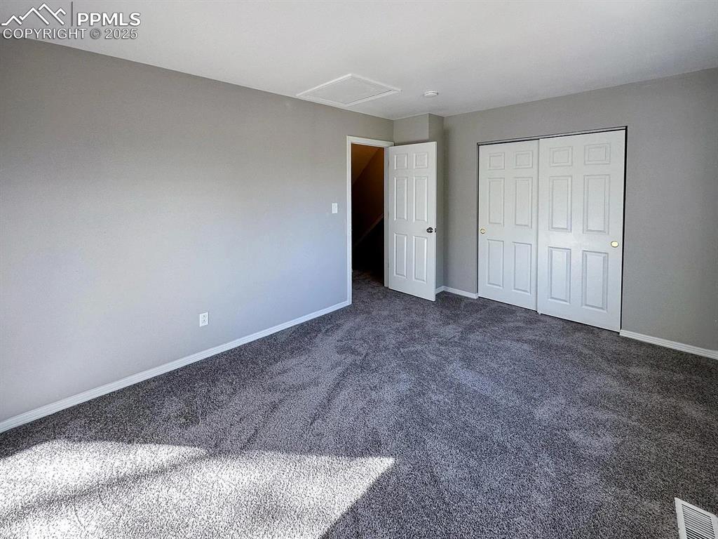 Image 12 of 23: Unfurnished bedroom featuring visible vents, baseboards, dark colored carpe