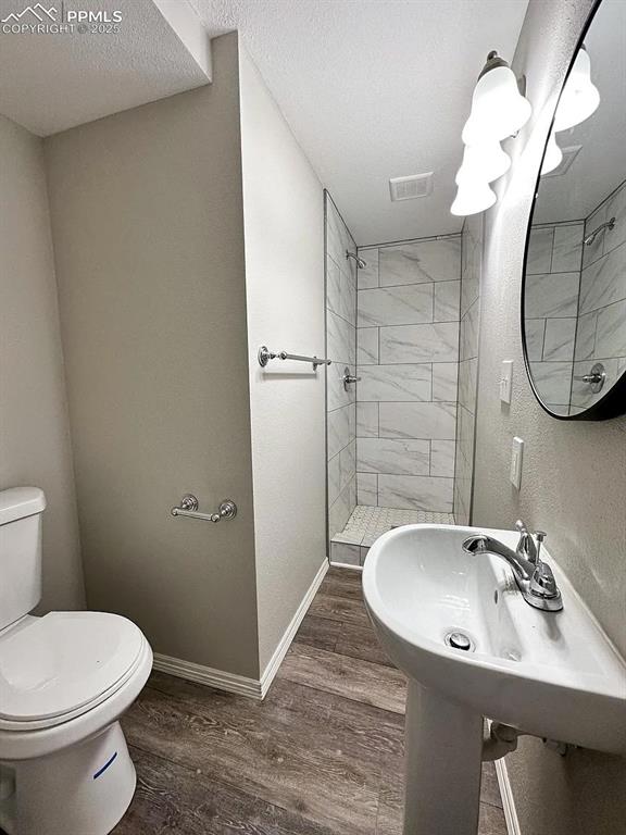 Image 21 of 23: Full bath featuring toilet, a textured ceiling, wood finished floors, and b