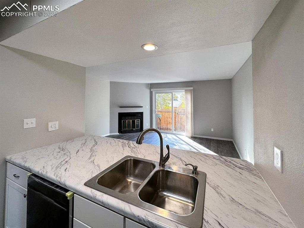 Image 6 of 23: Kitchen featuring baseboards, open floor plan, a fireplace with flush heart