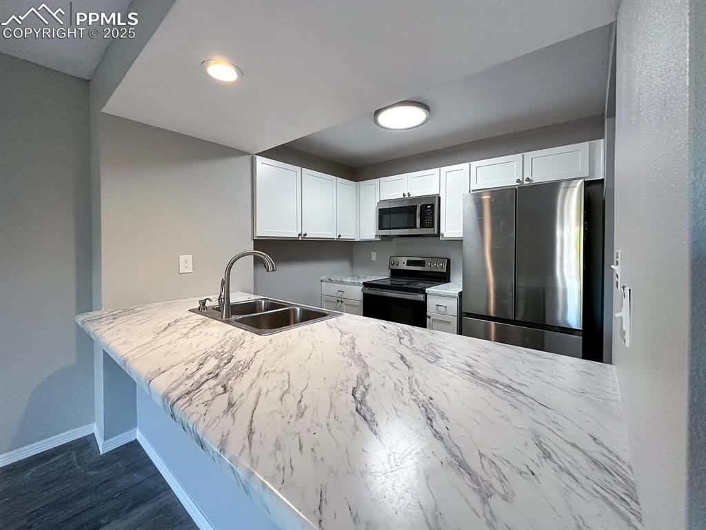 Image 7 of 23: Kitchen with a peninsula, white cabinets, appliances with stainless steel f