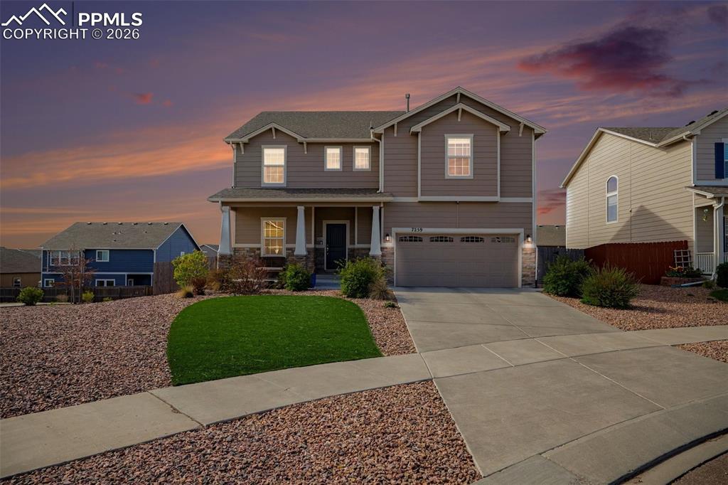 Caption: Two-story residence featuring composite siding, a covered front porch with columns, an attached two-
