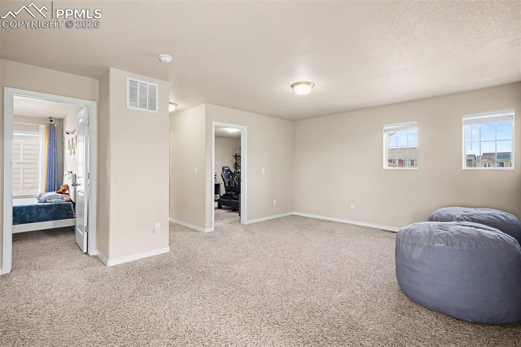 Image 22 of 40: Carpeted interior area with neutral wall tones and two windows