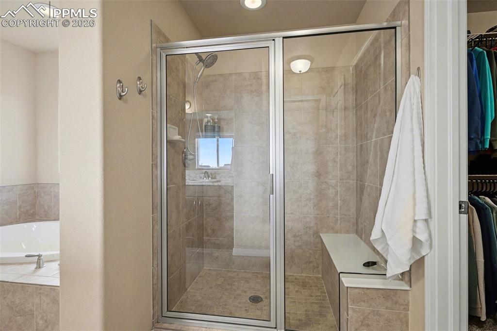 Image 24 of 40: Glass-enclosed shower featuring a built-in bench, tile surround, and a corn