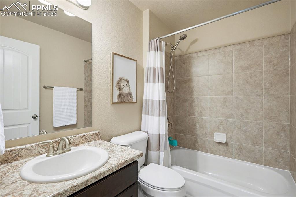 Image 25 of 40: Bathroom featuring a vanity with an integrated sink, a speckled countertop,
