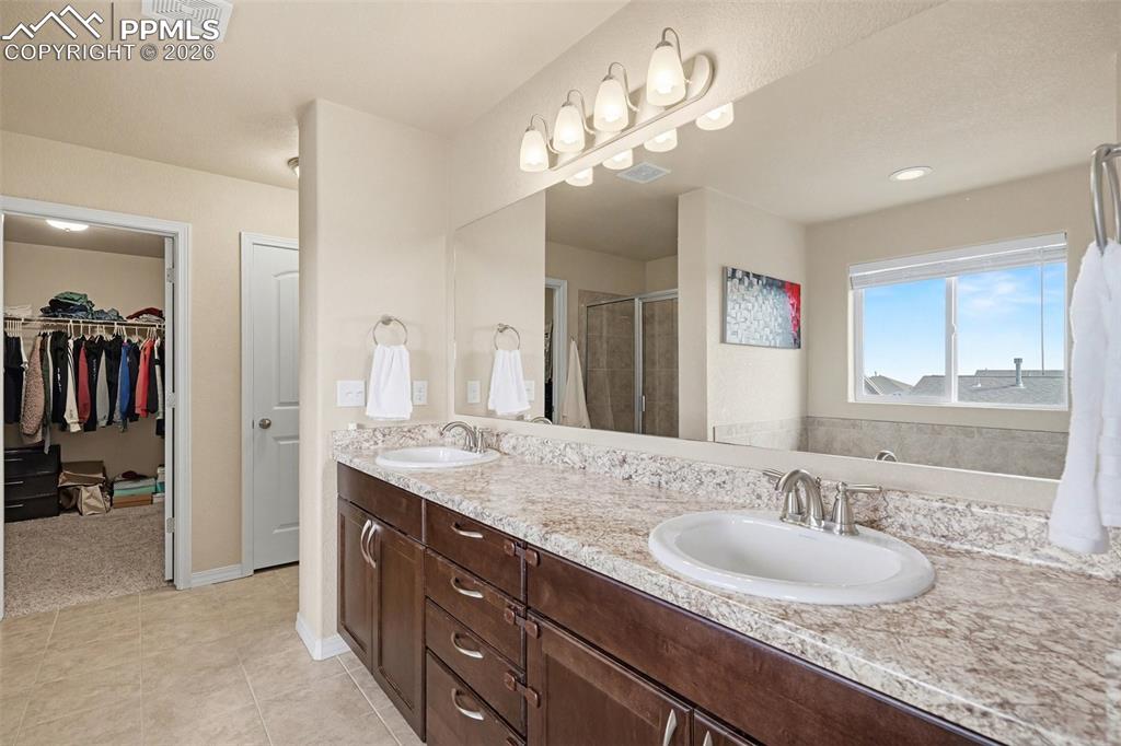 Image 26 of 40: Double vanity with wood-finish cabinetry and light-toned countertops