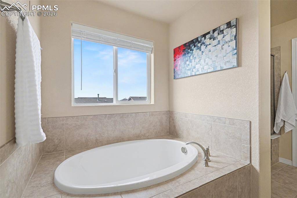 Image 27 of 40: Built-in soaking tub with brushed nickel fixtures, surrounded by light-tone