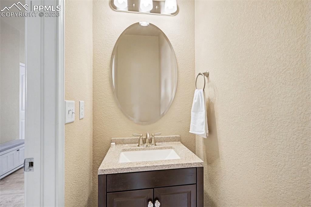 Image 28 of 40: Vanity area featuring a dark wood-finish cabinet with white hardware, a spe