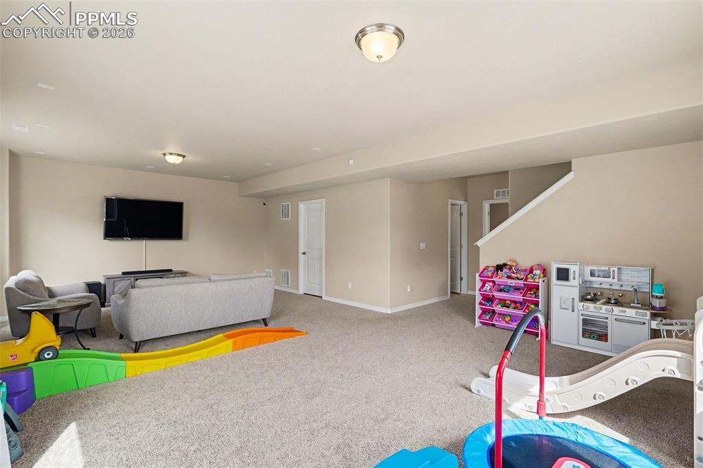 Image 35 of 40: Spacious finished basement with neutral carpeting, recessed lighting, and a