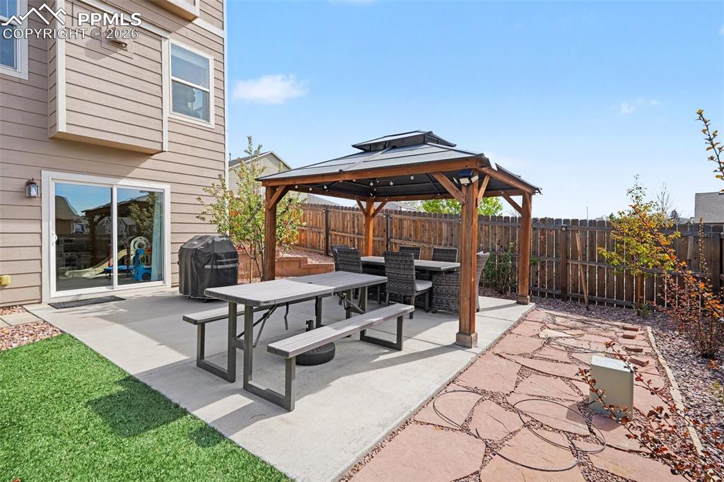 Image 38 of 40: Outdoor patio featuring a wooden gazebo, concrete slab, flagstone pathway, 