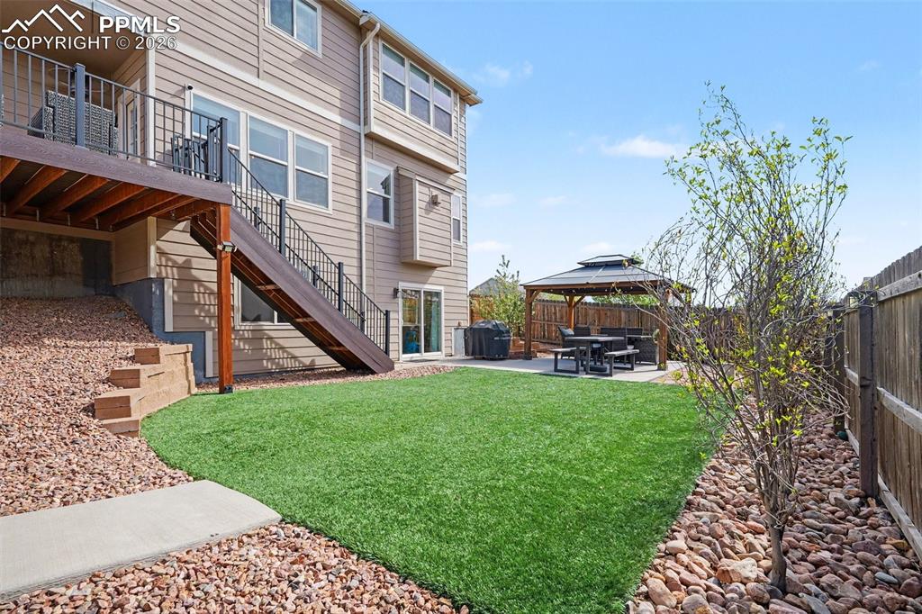 Image 39 of 40: Backyard featuring artificial turf, a spacious elevated deck with dark rail