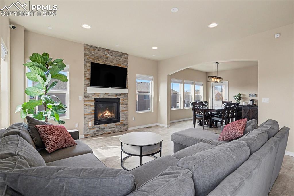 Image 4 of 40: Spacious living area featuring a stacked stone fireplace with a white mante