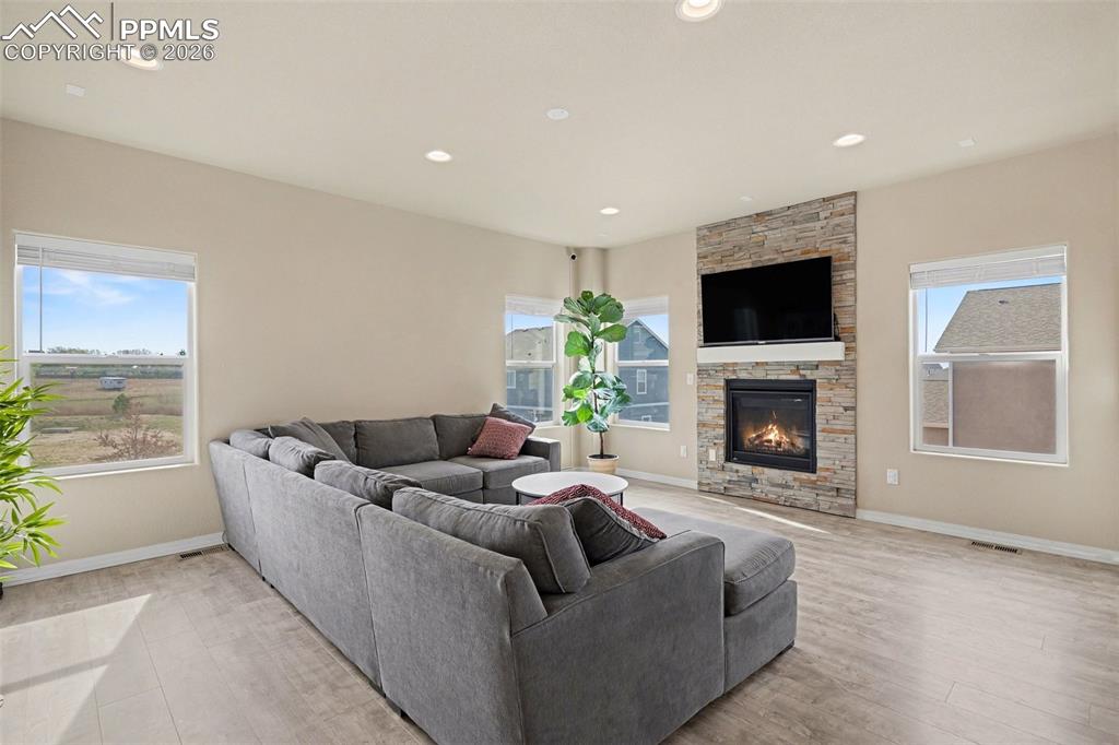 Image 5 of 40: Spacious living area featuring a stacked stone fireplace with a built-in ma